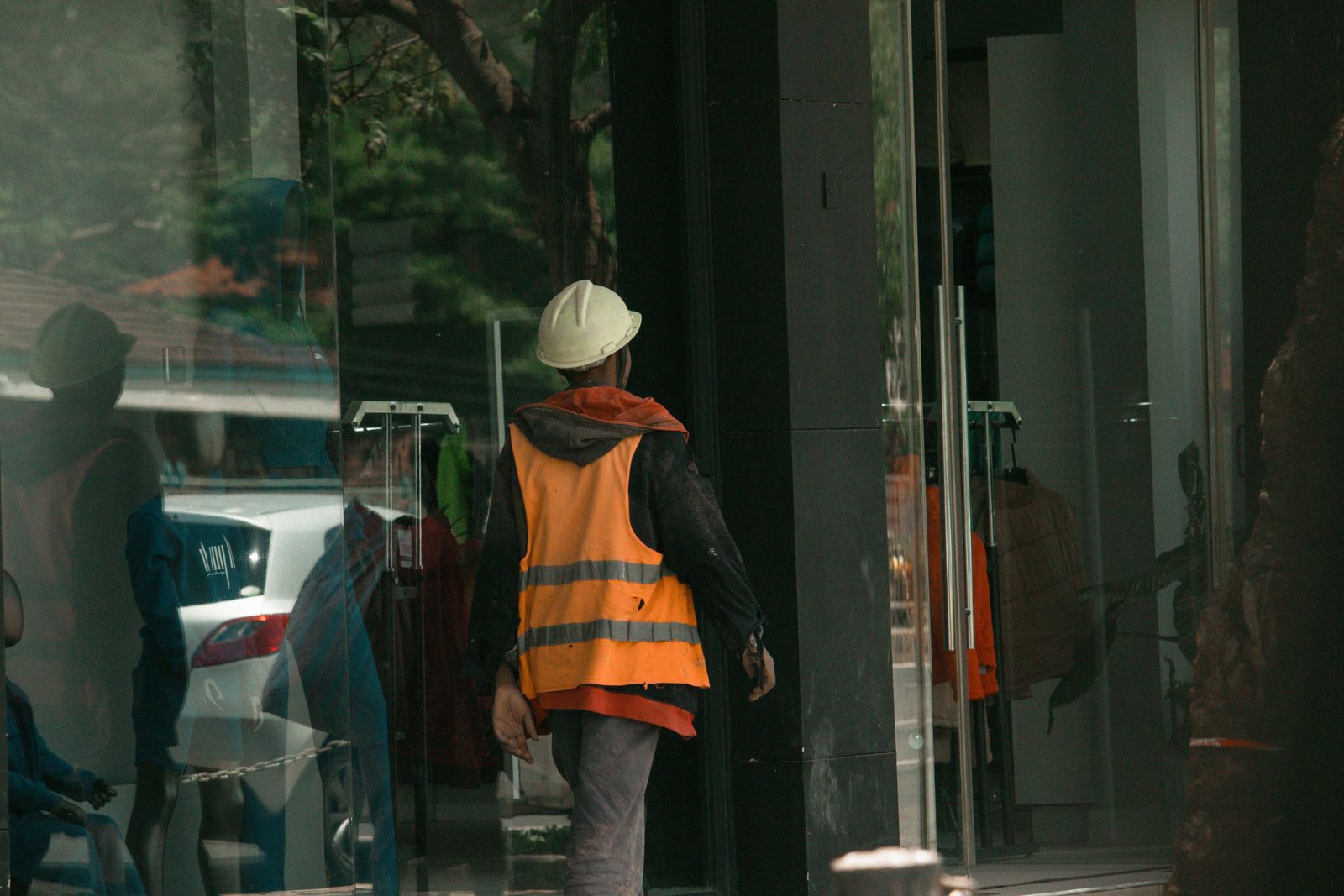 Construction worker in a reflective vest seen through a glass storefront in Nairobi.